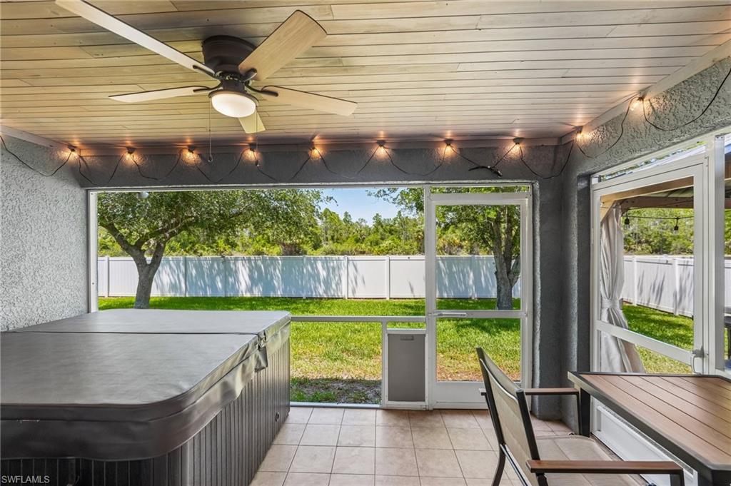 Screened patio featuring a ceiling fan, string lighting, and tiled flooring