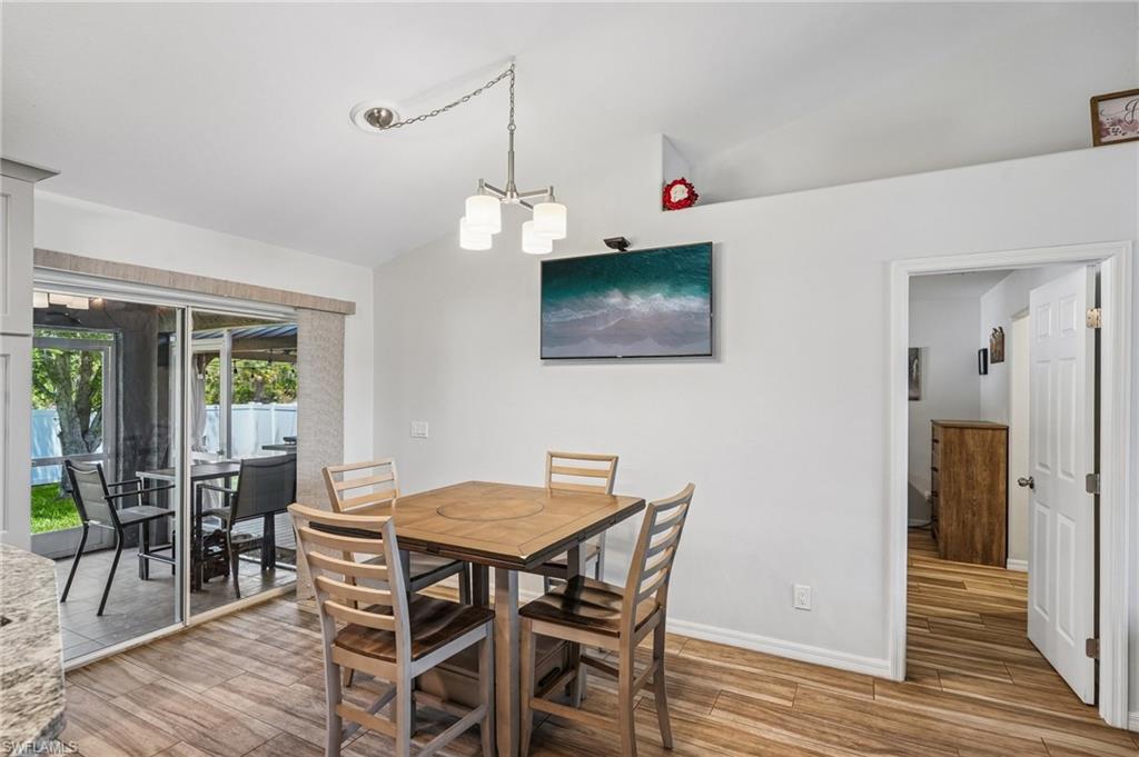 Dining area featuring wood-finish flooring, a contemporary chandelier, and direct access to an enclosed patio through sliding glass doors