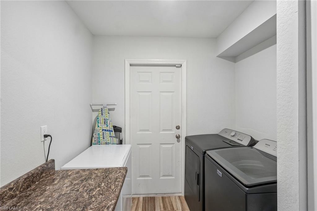 Dedicated laundry area featuring a patterned laminate countertop, wood-finish flooring, and a solid panel door