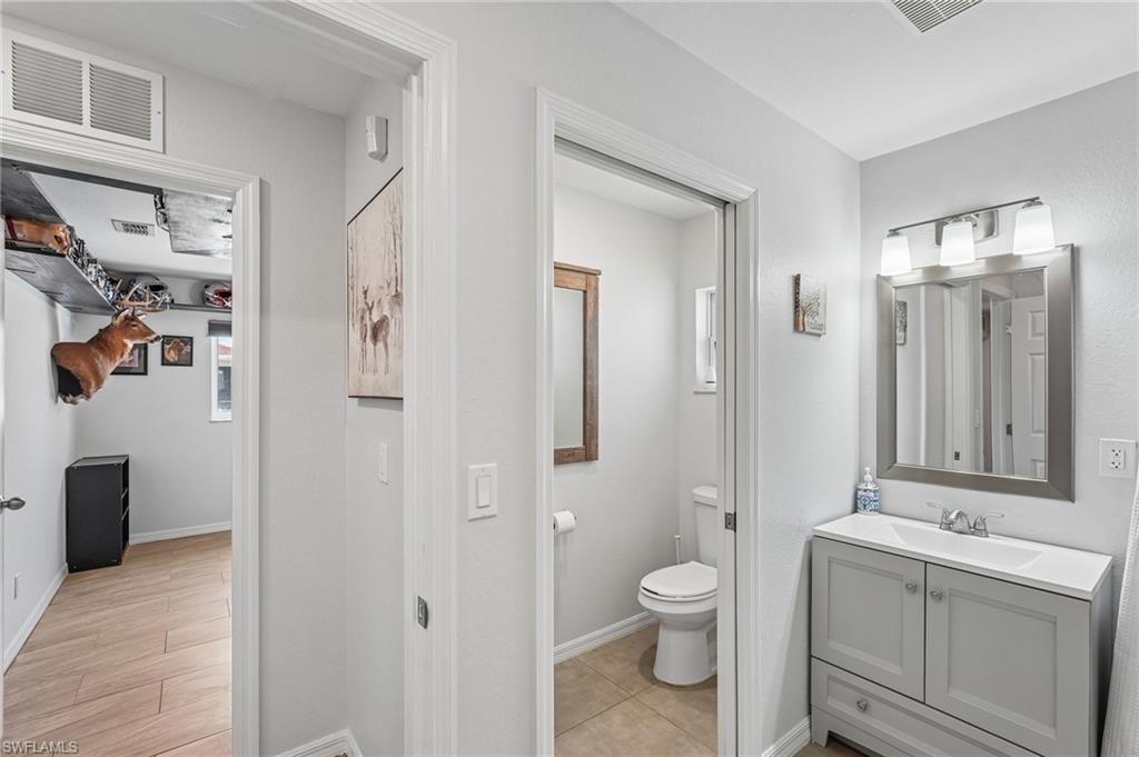Bathroom featuring a gray vanity with an integrated sink, a framed wall mirror, and a three-light fixture