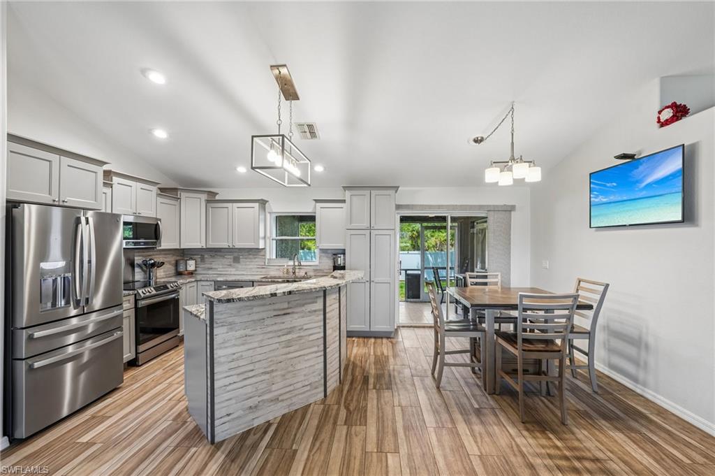 Modern kitchen featuring light gray cabinetry, stainless steel appliances, and wood-finish flooring
