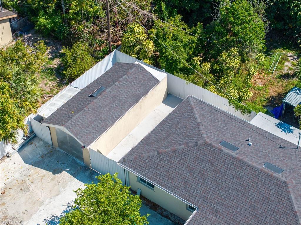 Residential property featuring a shingle roof, skylights, and a detached structure with a pitched roof