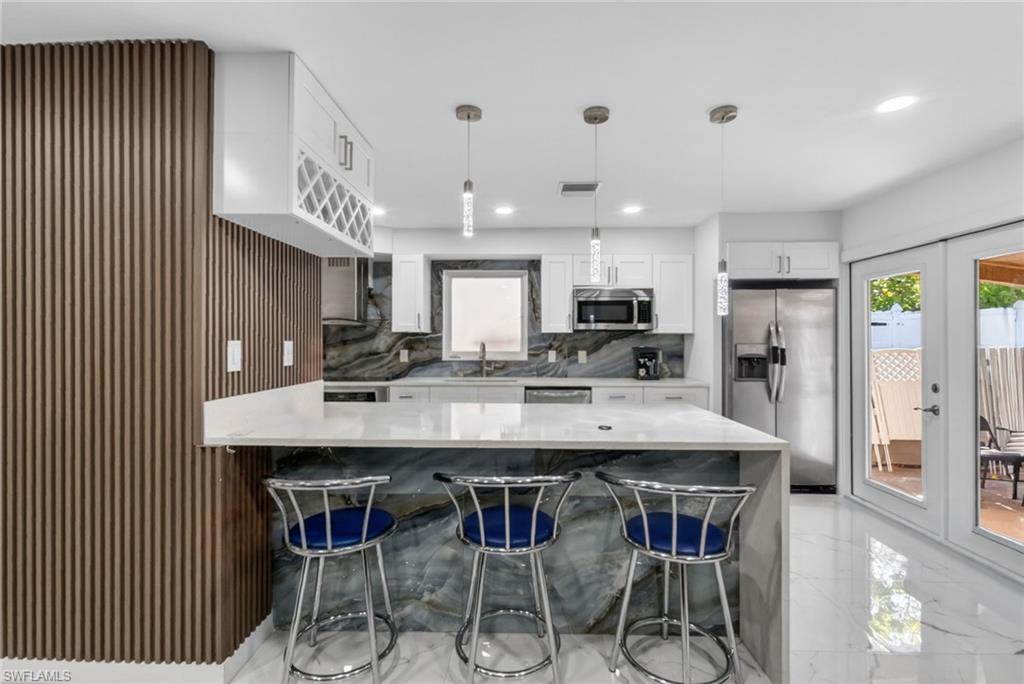Modern kitchen featuring a large center island with integrated seating, white cabinetry, a built-in wine rack, and stainless steel appliances