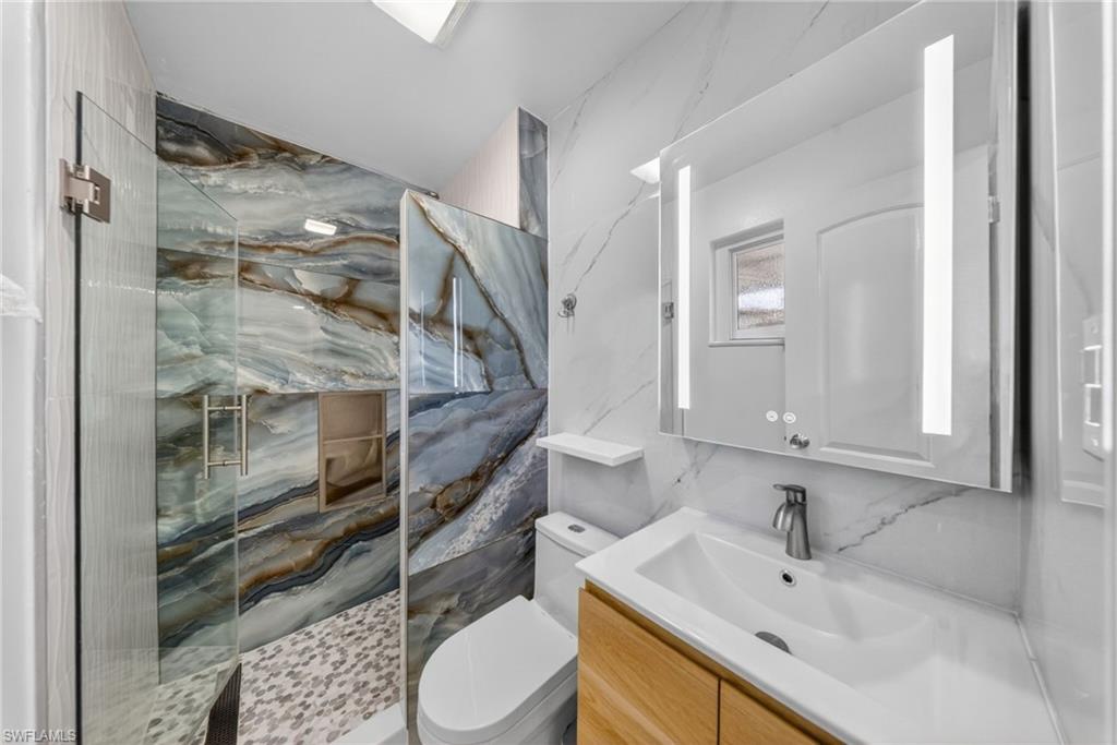 Contemporary bathroom featuring a walk-in shower with patterned wall tile and pebble flooring