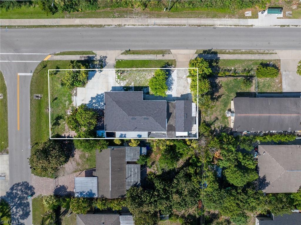 Property featuring a dark shingle roof, a concrete driveway, and surrounding green landscaping
