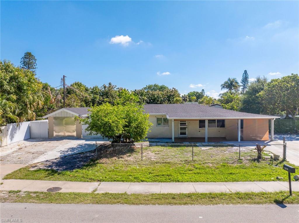 Single-story residence featuring a carport, covered porch, and a fenced front yard