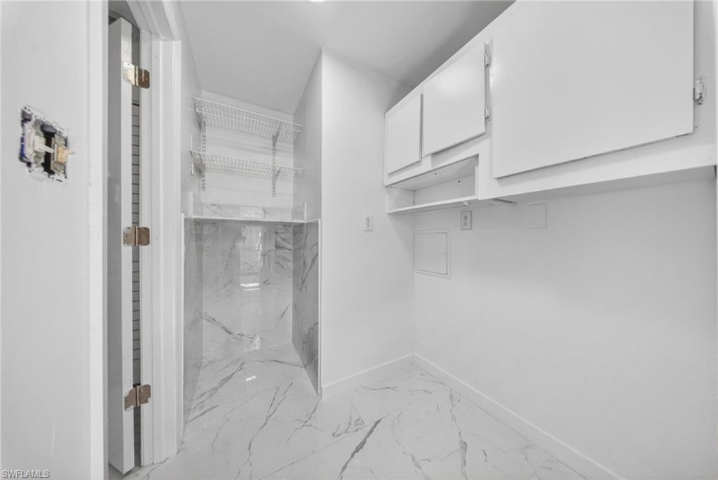 Utility space featuring white cabinetry, built-in shelving, and a patterned tile floor