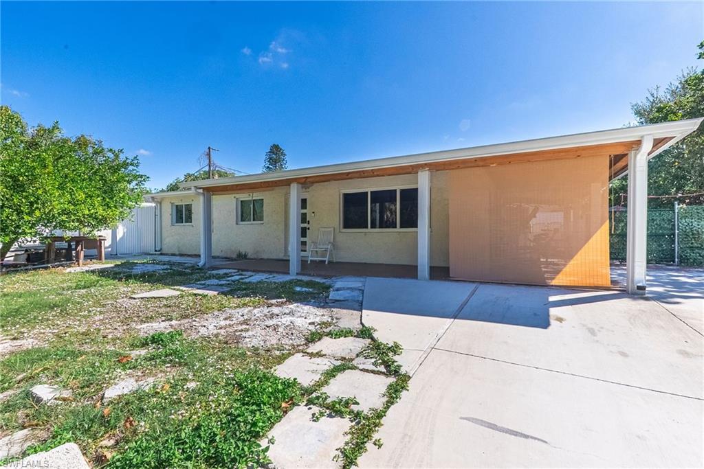Rear exterior with a covered patio, multiple windows, and a concrete driveway