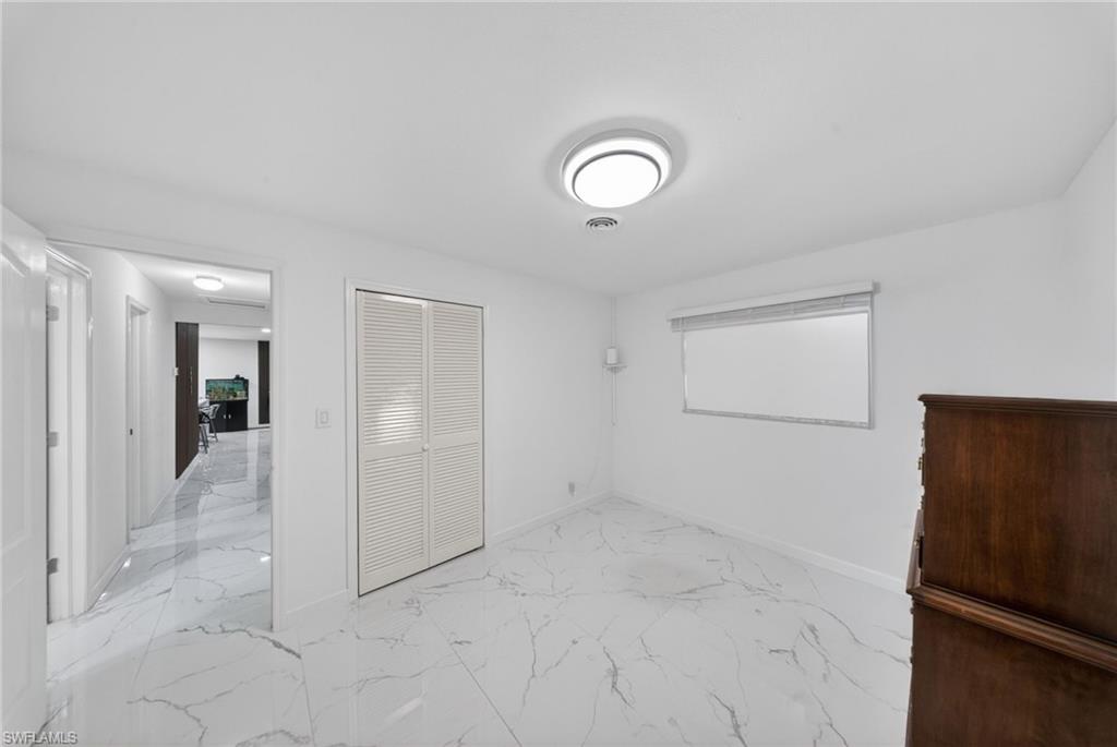 Bright room featuring white walls and white marble-look flooring