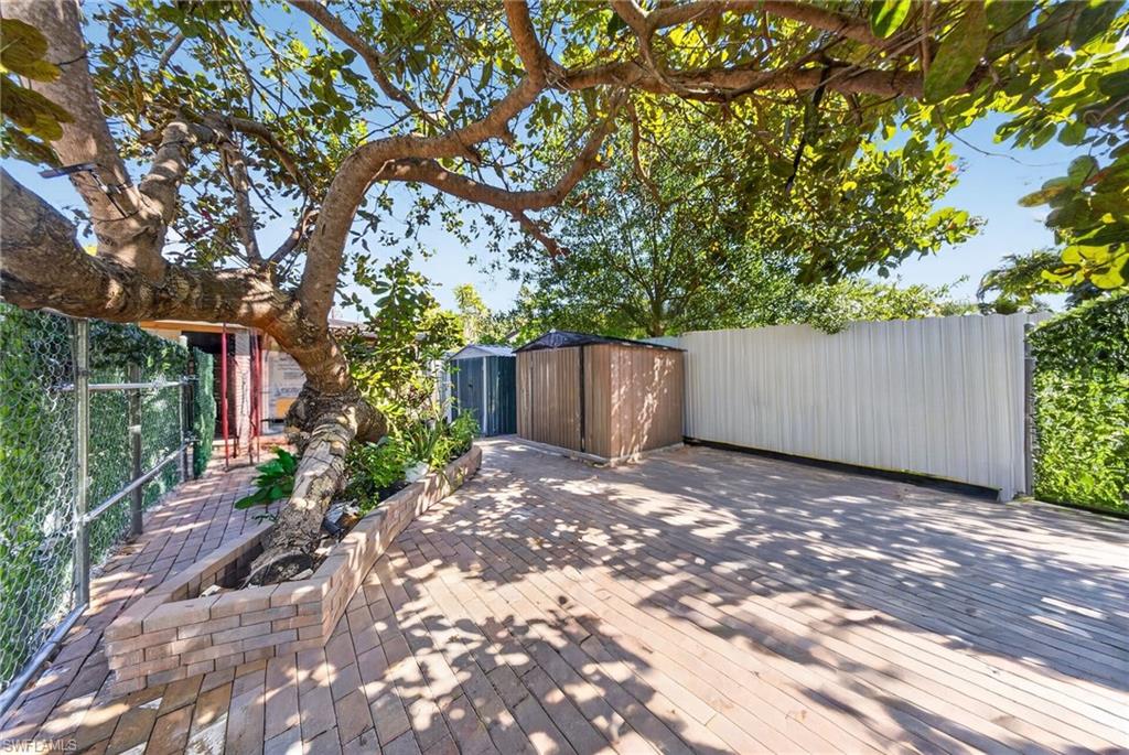 Expansive outdoor area featuring wood-finish decking and a large mature tree