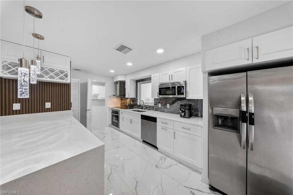 Contemporary kitchen featuring white cabinetry, stainless steel appliances, and white stone countertops