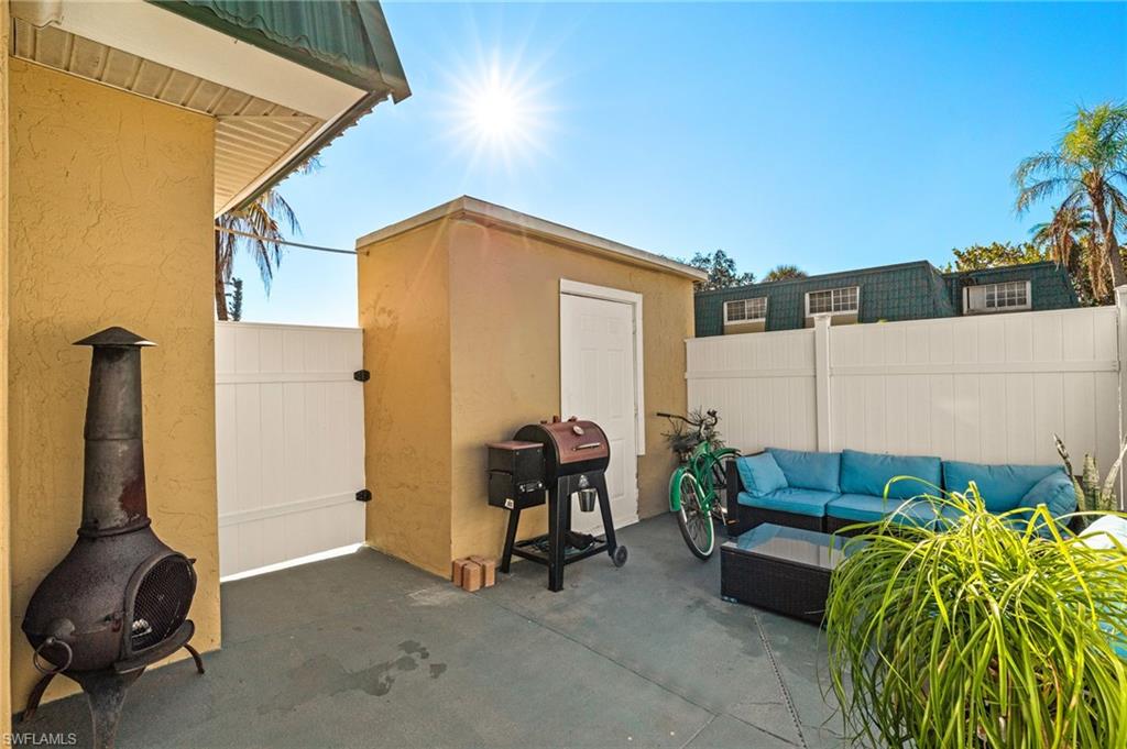 View of patio featuring area for grilling and a shed