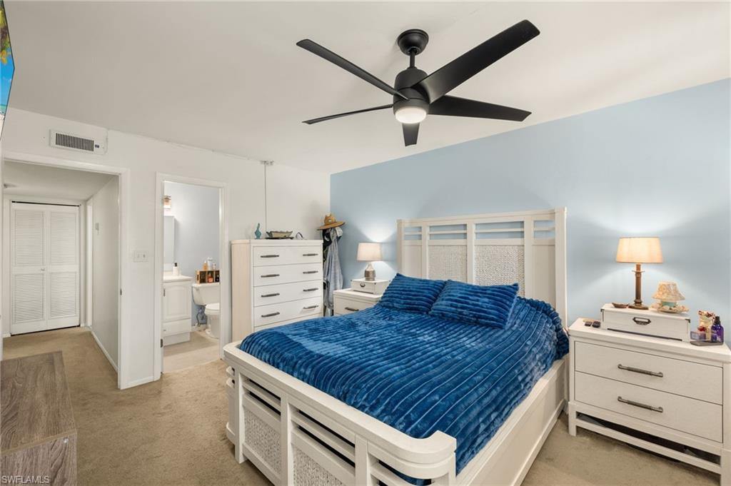 Bedroom with light carpet, ensuite bath, and ceiling fan