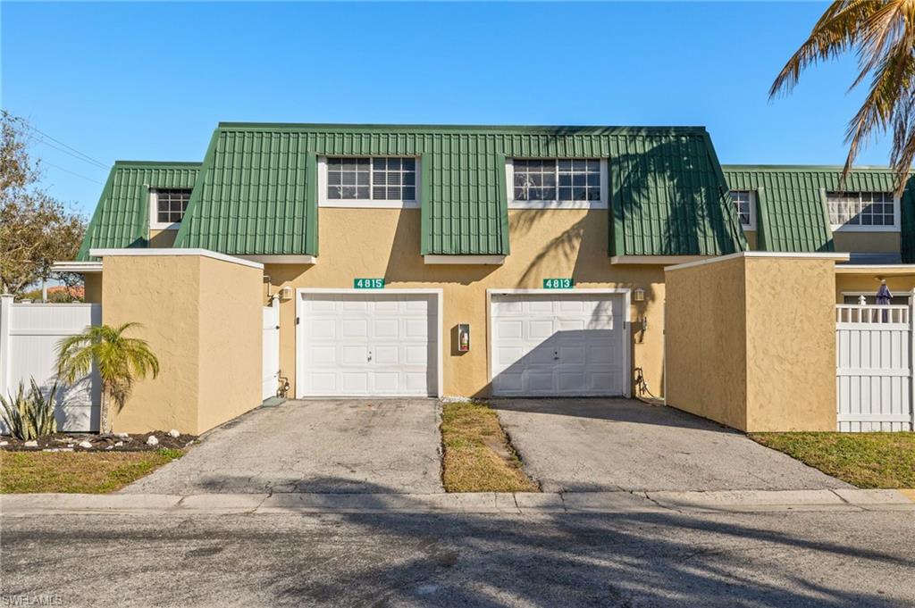 Townhome / multi-family property featuring stucco siding, driveway, and mansard roof