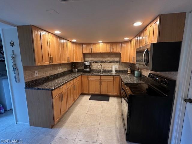Kitchen featuring black electric range oven, stainless steel microwave, light tile patterned floors, decorative backsplash, and recessed lighting