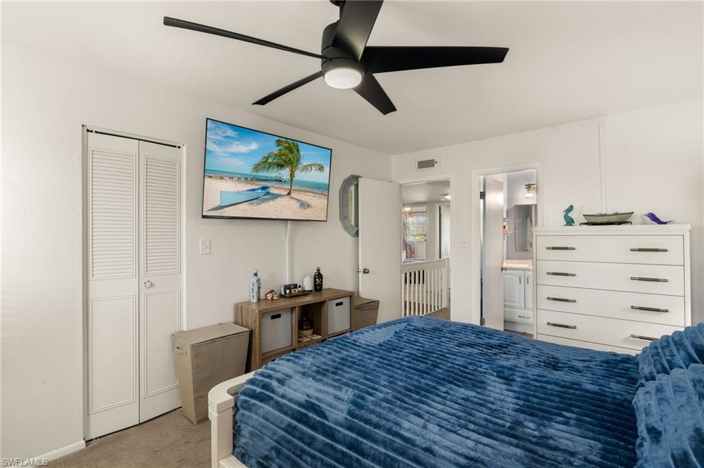 Bedroom with light colored carpet, ceiling fan, and a closet