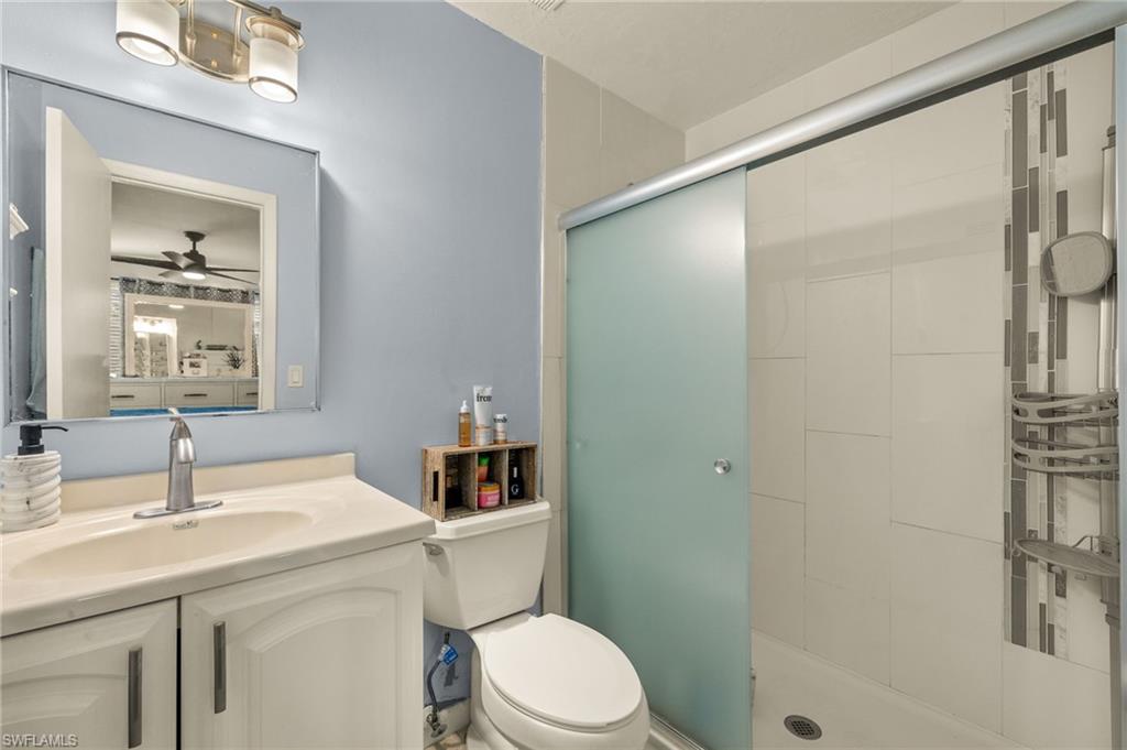 Bathroom featuring a shower stall, a ceiling fan, and vanity