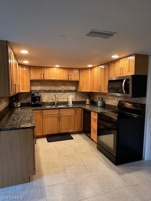 Kitchen with black appliances, tasteful backsplash, light tile patterned floors, dark stone counters, and recessed lighting