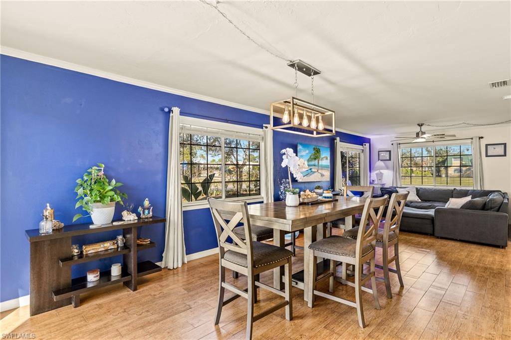 Dining space featuring wood-type flooring, ceiling fan, ornamental molding, and a chandelier