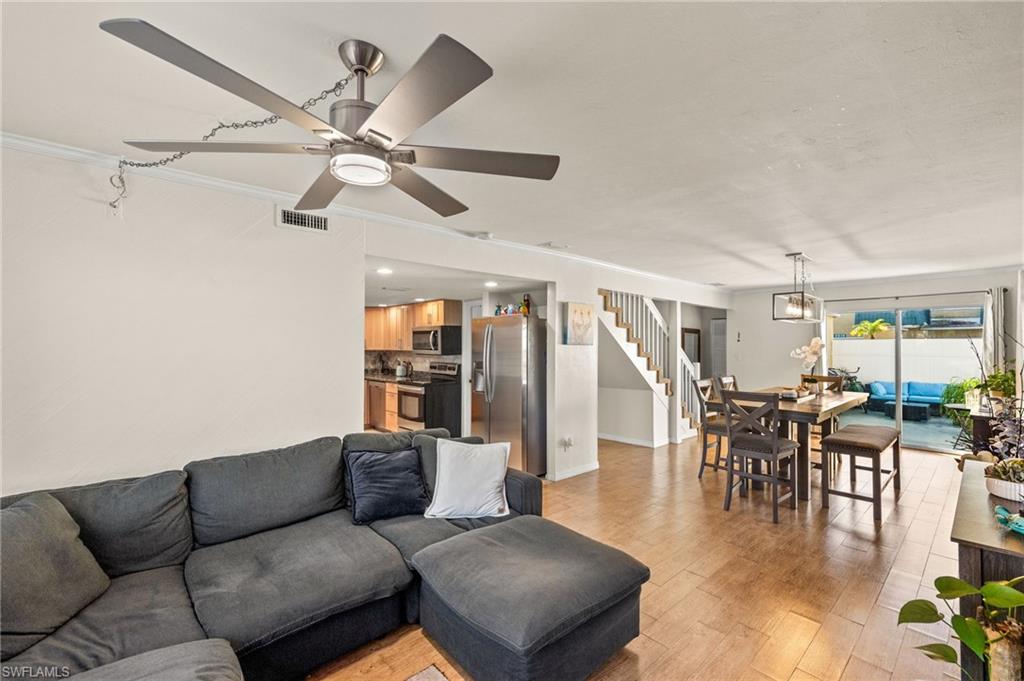Living area featuring light wood-type flooring, crown molding, ceiling fan, and stairs