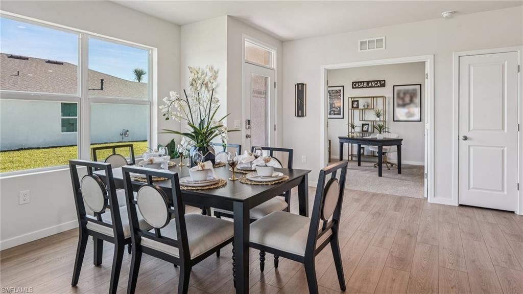 Dining area featuring wood-finish flooring, a large window overlooking the backyard, and direct access to an adjacent room