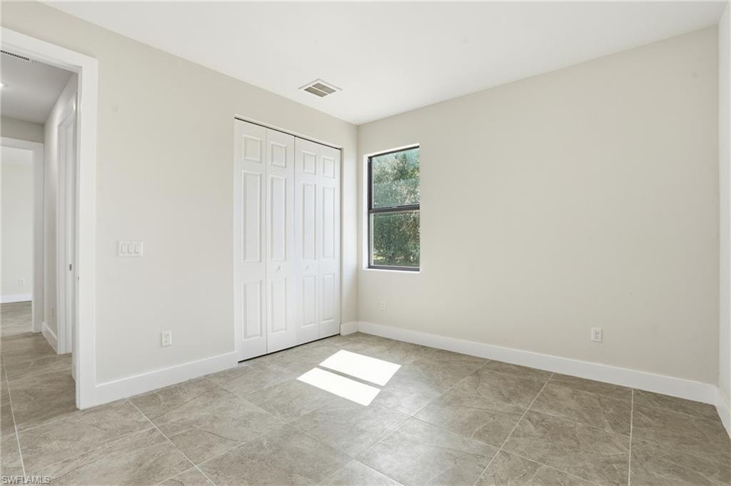 Room featuring neutral-toned walls, tiled flooring, a single window, and bi-fold closet doors