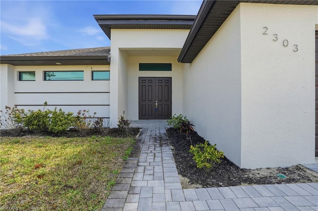 Contemporary exterior featuring a recessed entry, dark double doors, and a paver walkway