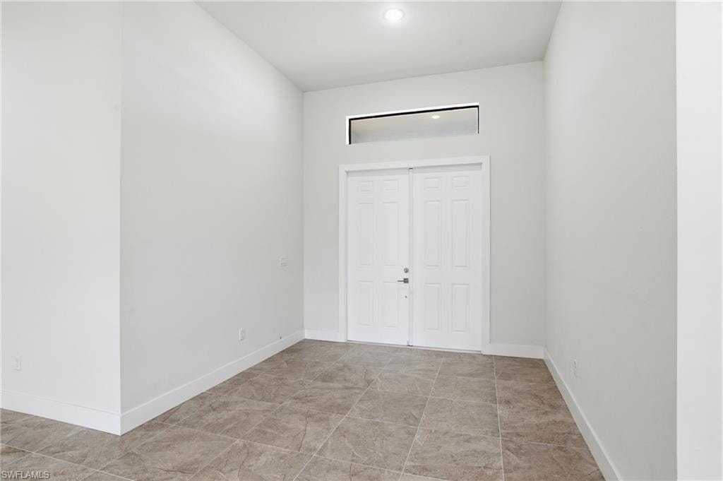 Entryway featuring double panel doors with transom window, recessed lighting, and large format floor tiles