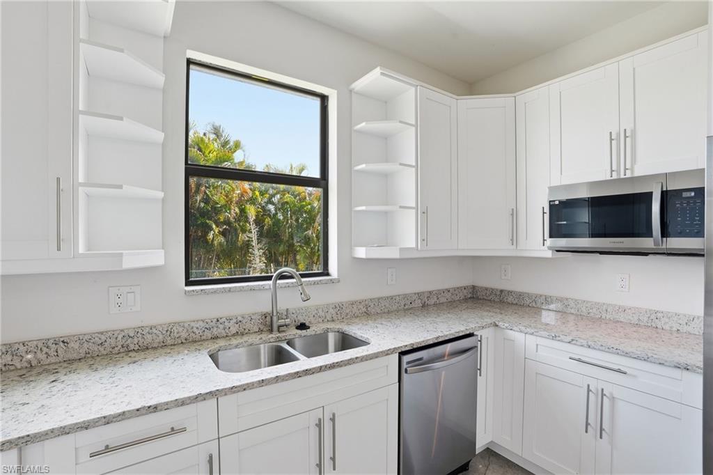 Modern kitchen featuring white shaker cabinetry, stainless steel appliances, granite countertops, and a double basin sink with a gooseneck faucet