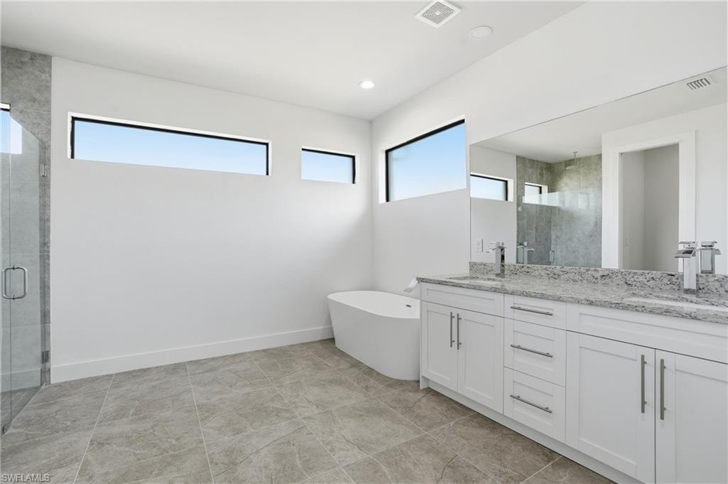 Spacious bathroom featuring a dual vanity with white cabinetry and stone countertops