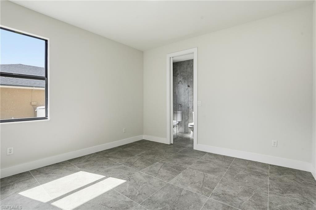 Spacious room featuring neutral painted walls, large format grey tile flooring, and a window with black trim