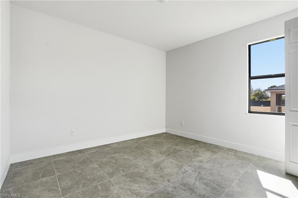 Room featuring white walls, gray tile flooring, a single window with black trim, and white baseboards