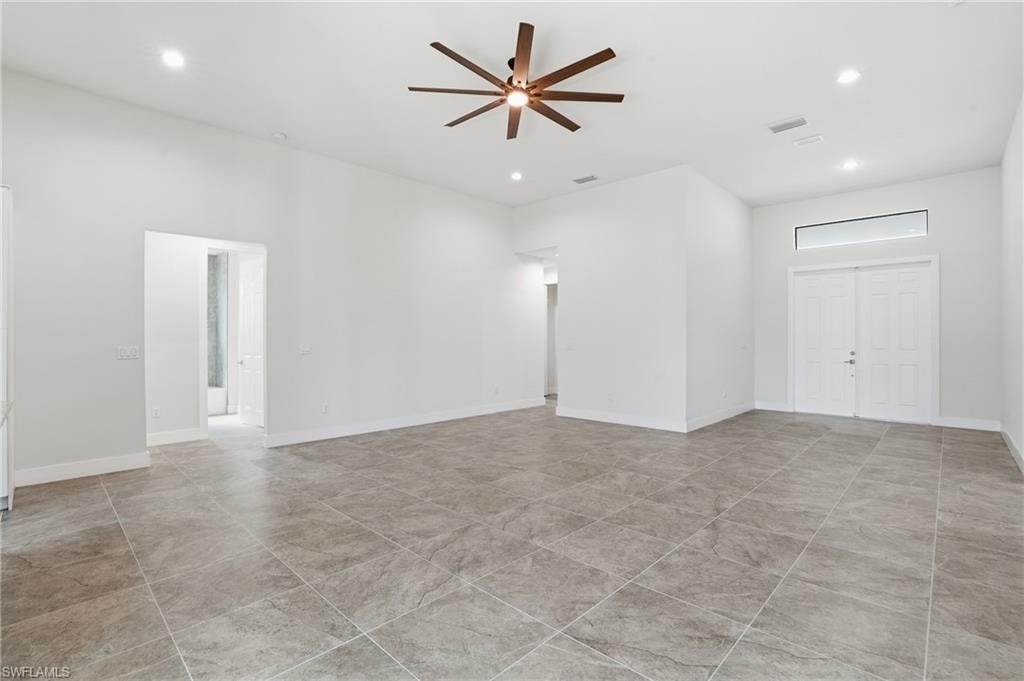 Spacious interior featuring large format tile flooring, high ceilings with recessed lighting, and a modern ceiling fan