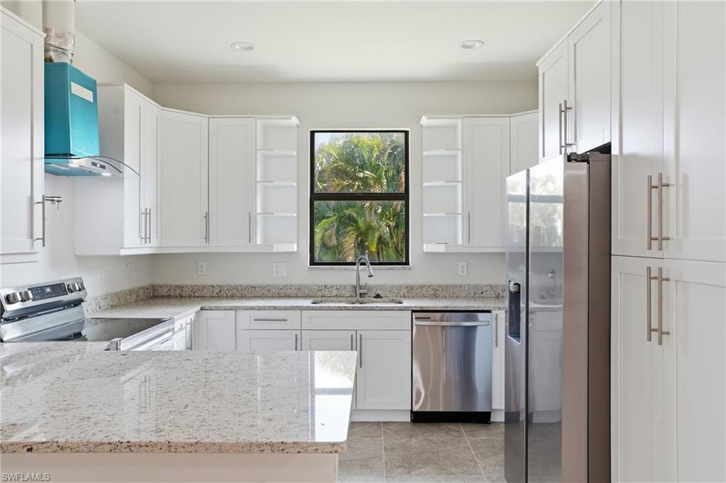Kitchen featuring white shaker-style cabinetry with brushed nickel hardware, light-toned granite countertops, and stainless steel appliances