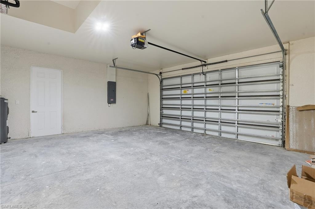 Spacious garage with a concrete floor, overhead lighting, and a durable roll-up garage door