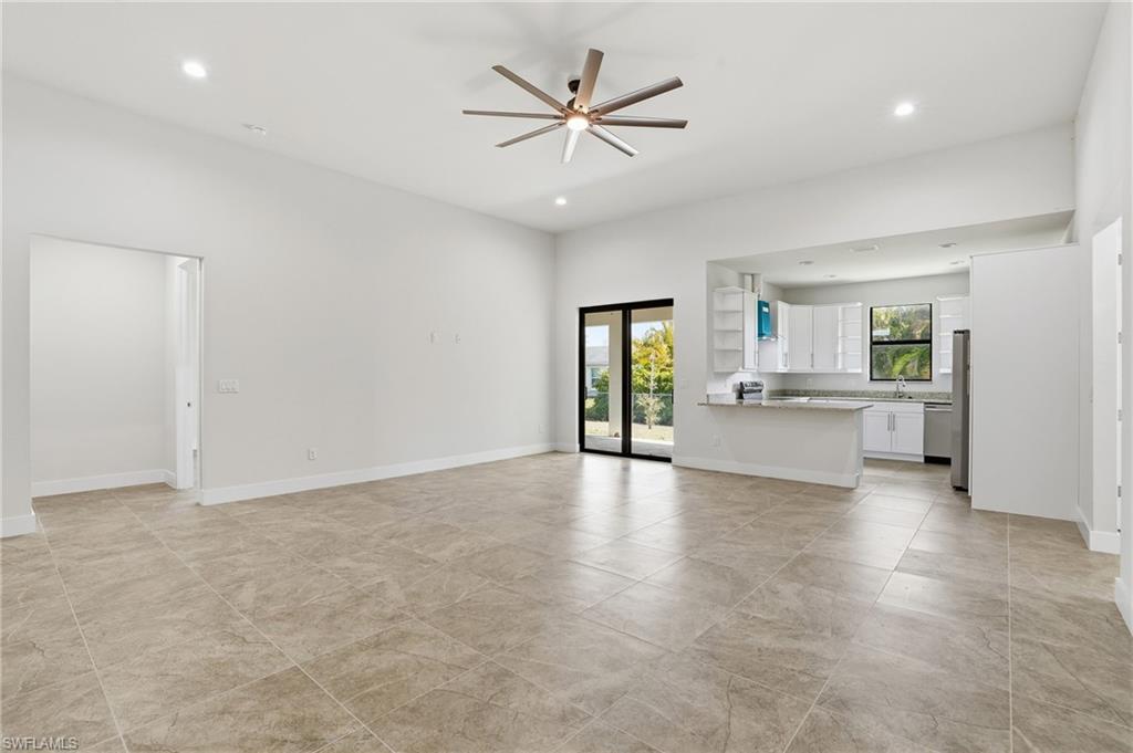 Expansive open-concept living area featuring large format tile flooring, a modern ceiling fan, recessed lighting, and a sliding glass door to the exterior
