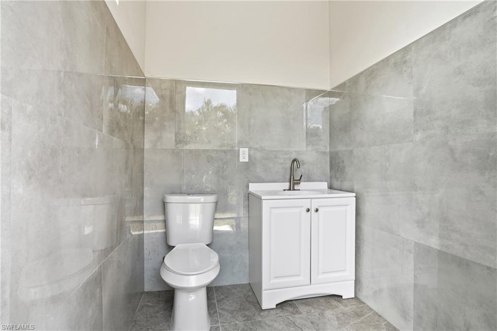 Bathroom featuring a white vanity with a single basin sink, brushed nickel faucet, and white cabinetry