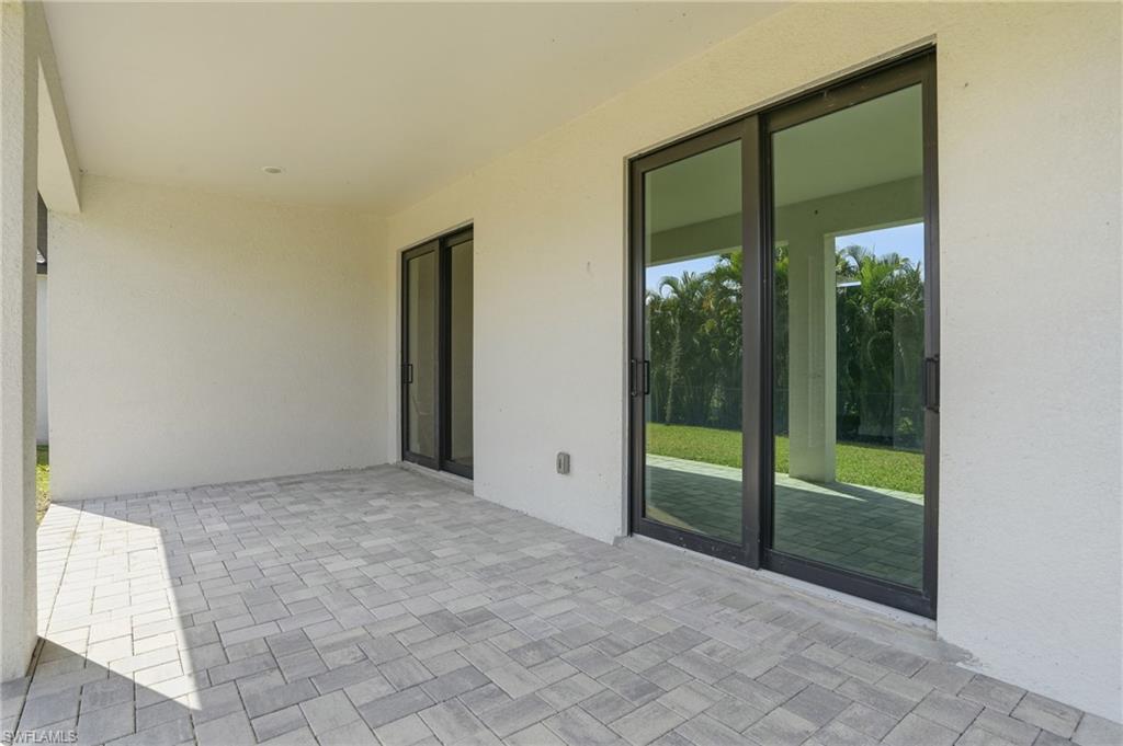 Covered patio with paver flooring, multiple sliding glass doors, and recessed lighting