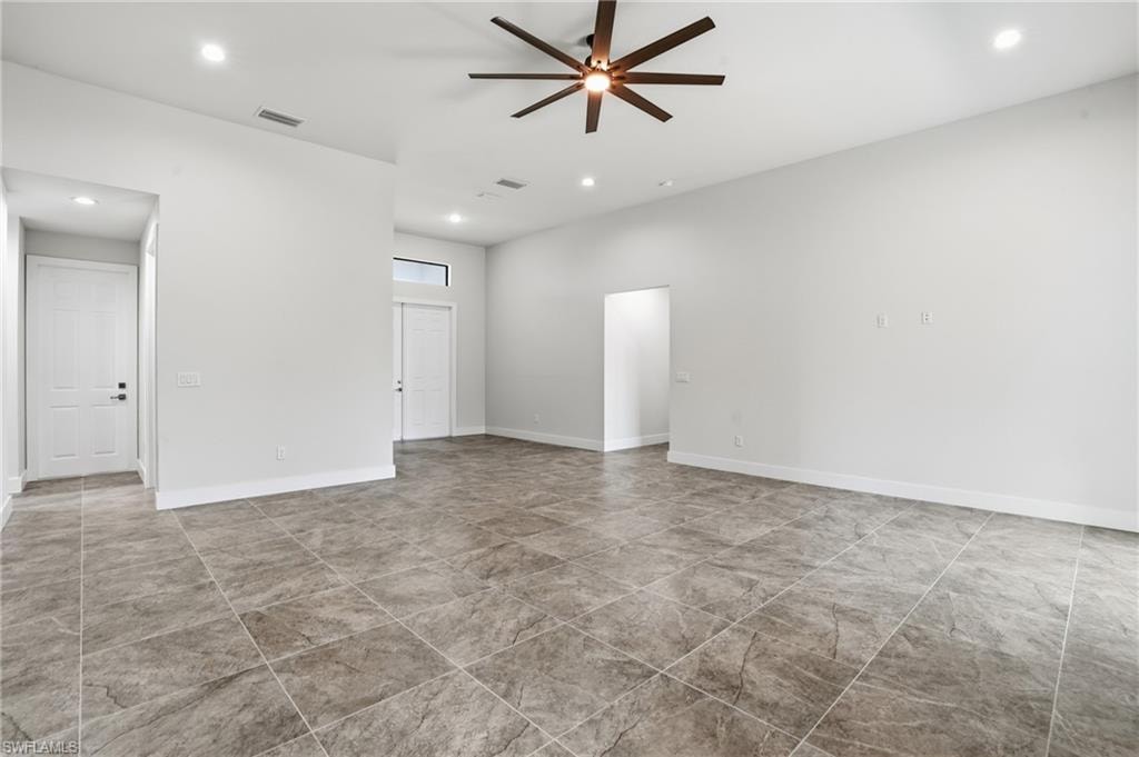 Spacious interior featuring large format tile flooring, high ceilings, recessed lighting, and a modern ceiling fan
