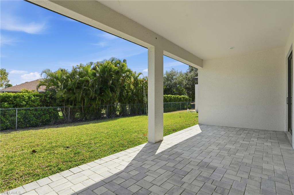 Covered patio with paver flooring, offering an expansive backyard space
