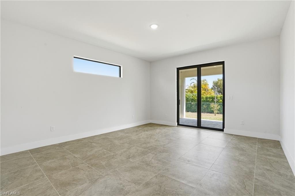 Expansive room featuring large format tile flooring, a horizontal transom window, and a glass sliding door providing direct outdoor access