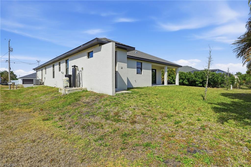 Spacious backyard featuring an expansive lawn and a covered patio area