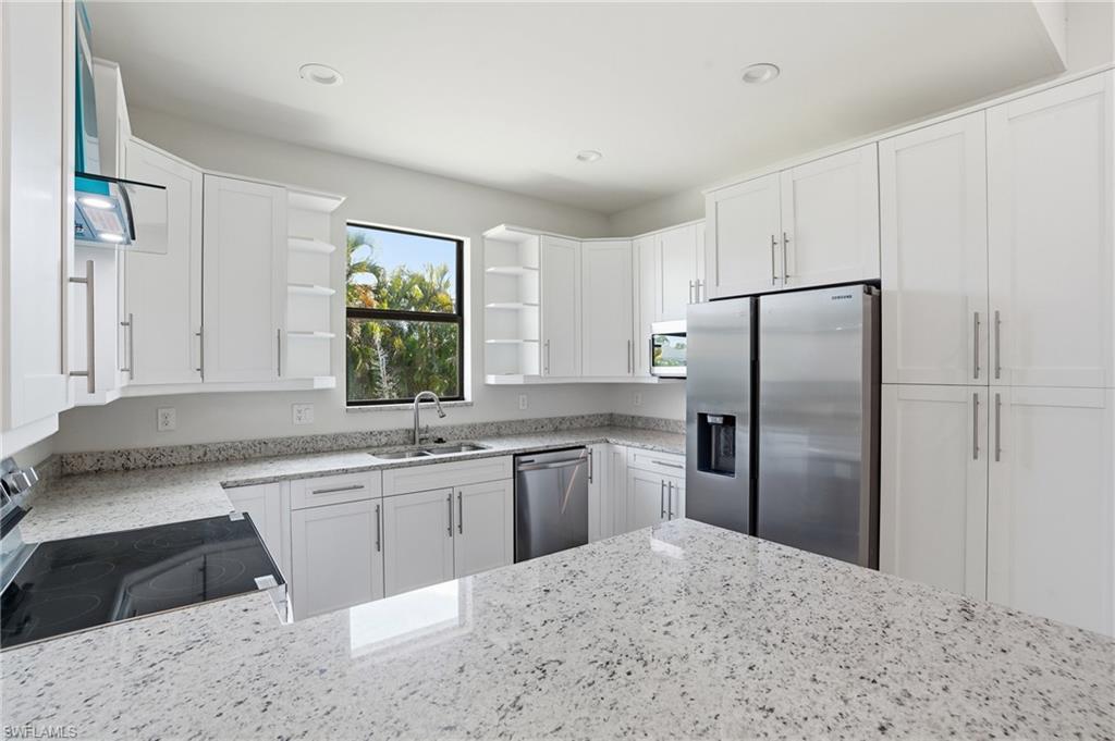Modern kitchen featuring white shaker-style cabinetry, granite-finish countertops, and stainless steel appliances