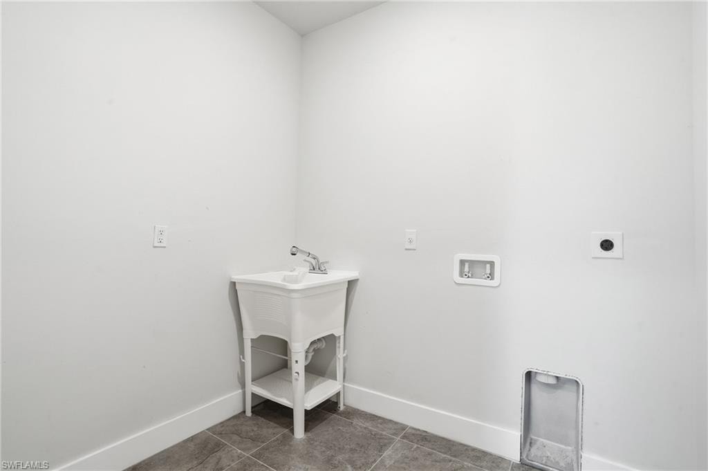 Laundry area featuring a utility sink, tile flooring, and appliance hookups