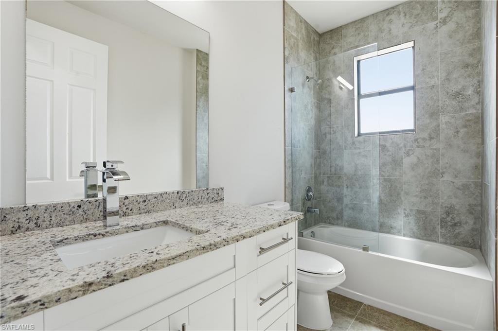 Bathroom featuring a white vanity with a speckled countertop, a chrome faucet, and a large mirror