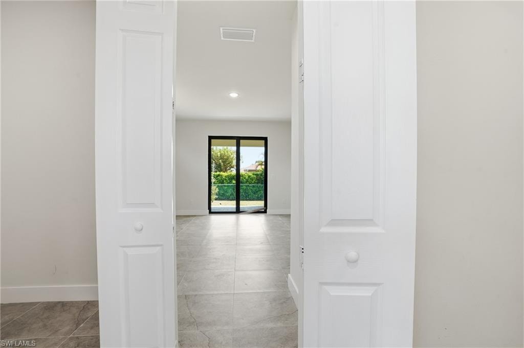 Interior space featuring neutral-toned tile flooring throughout, white walls, and recessed lighting