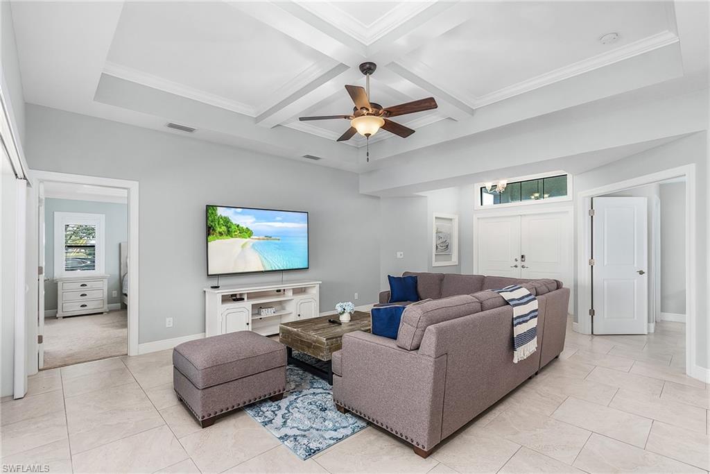 Living room with beam ceiling, coffered ceiling, visible vents, and baseboards