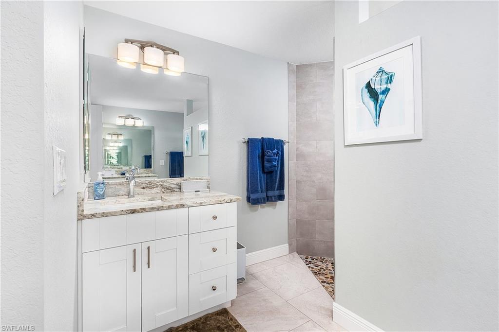 Full bathroom featuring walk in shower, vanity, and baseboards
