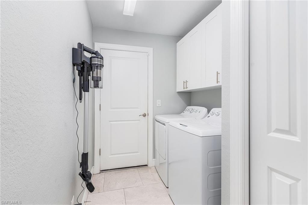 Washroom featuring cabinet space, independent washer and dryer, and light tile patterned floors