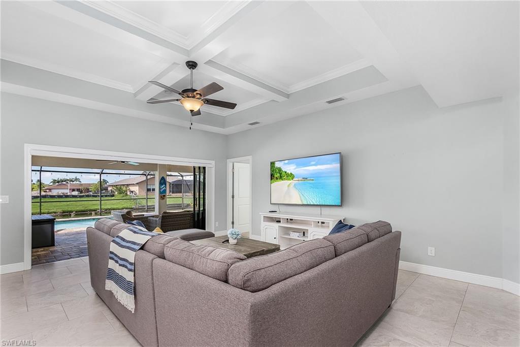 Living room featuring a sunroom, coffered ceiling, beamed ceiling, and baseboards